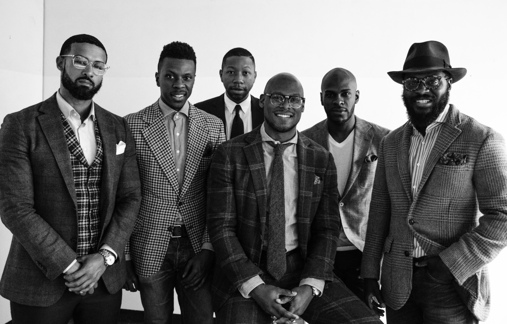 The Lives of Men community — group portrait of six men in tailored blazers